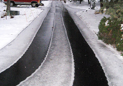An asphalt driveway with heated tire tracks.