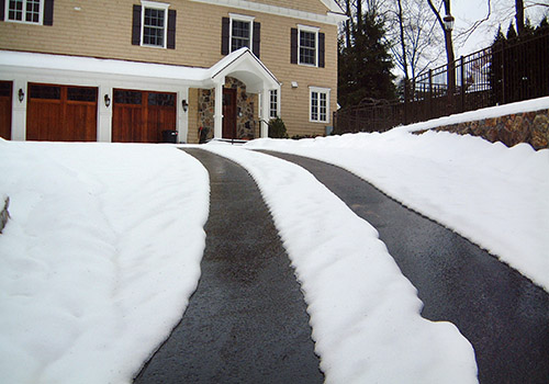 Heated tire tracks in an asphalt driveway.